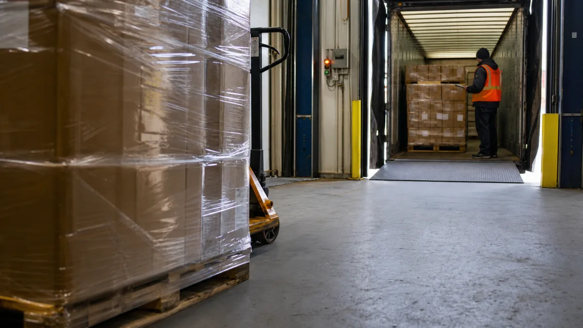 A worker receiving a wrapped pallet at a warehouse loading dock